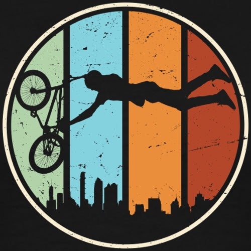 Silhouette of a person on a bike performing a trick against a colorful background with city skyline.