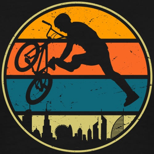 Silhouette of a person on a bike against a sunset sky with city skyline