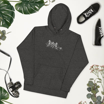 Dark gray hoodie with mountain design on a white background with plants and shoes.