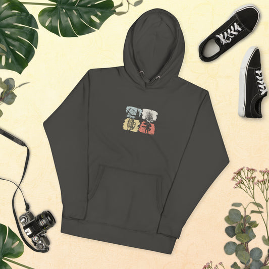 Dark grey hoodie with camping and equipment graphics on a beige background with plants and shoes.