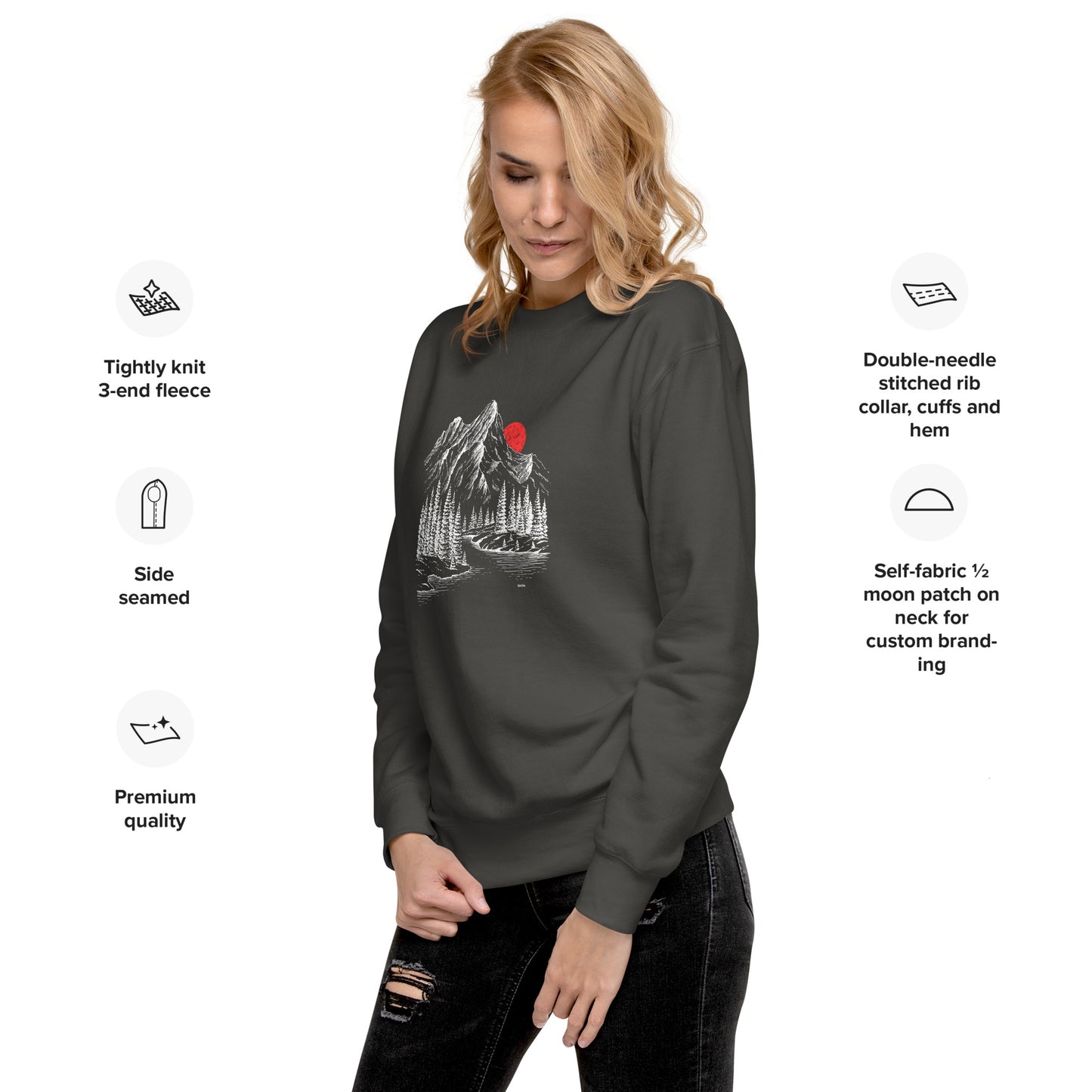 Woman wearing a dark gray sweatshirt with a graphic design mountain sketch forest on a white background, featuring text about sweatshirt features.