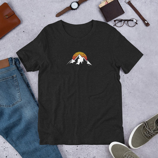 Black t-shirt with mountain design on a concrete surface with jeans, shoes, and accessories.