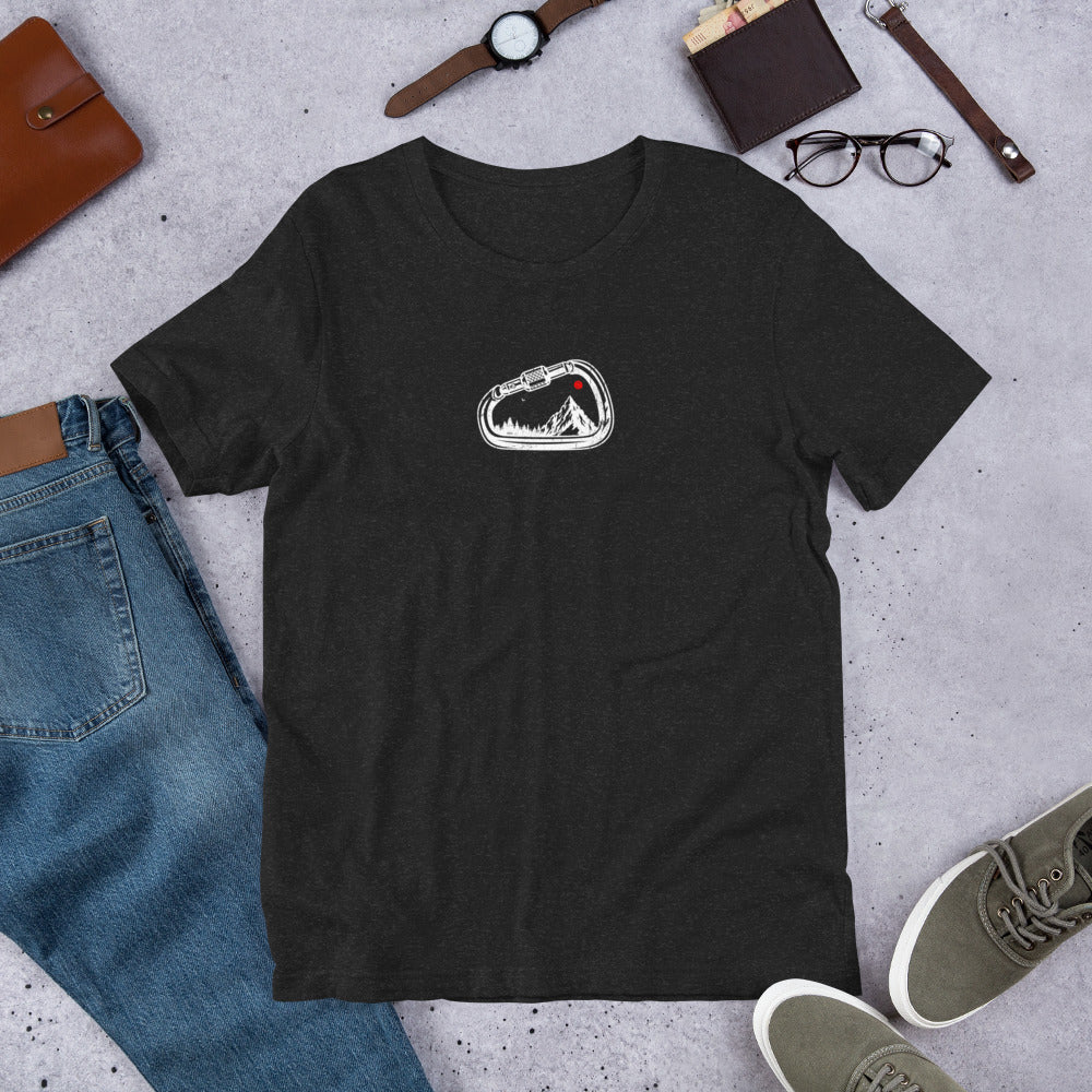 Black t-shirt with a white logo on a gray surface with jeans, shoes, and accessories.