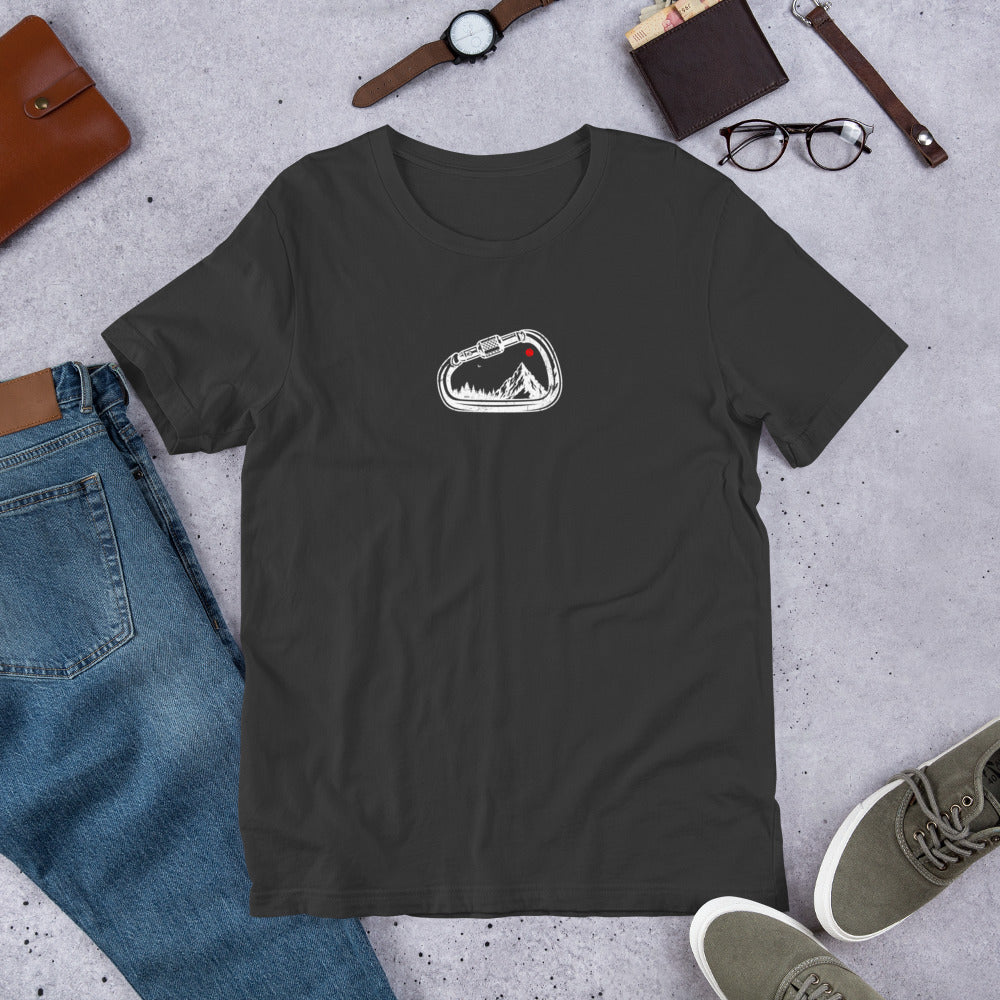 Black t-shirt with a logo on a gray surface with jeans, shoes, and accessories.