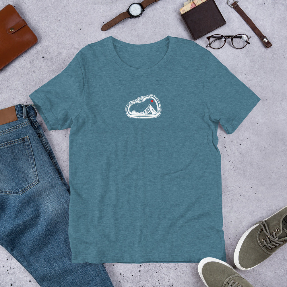 Blue t-shirt with a graphic design on a concrete surface with jeans, shoes, and accessories.