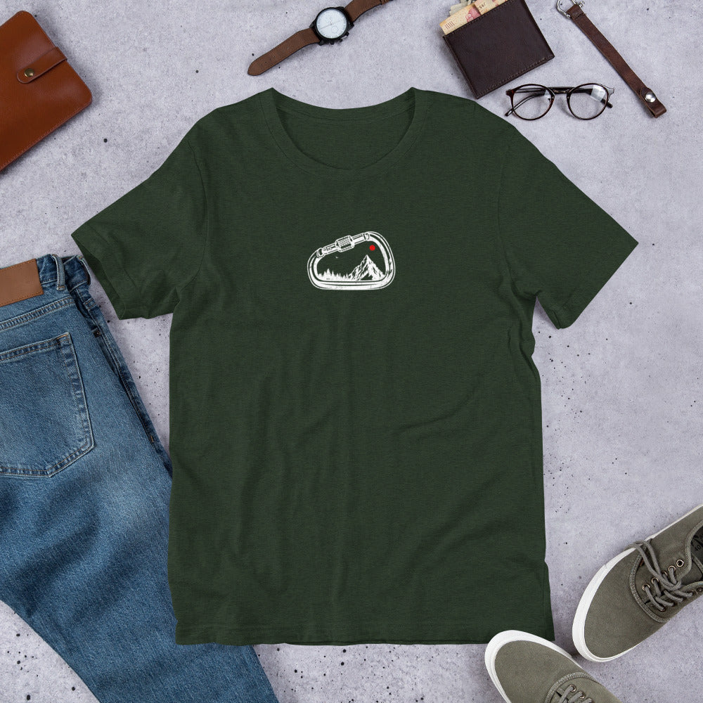 Green t-shirt with a white graphic on a gray surface with jeans, shoes, and accessories.