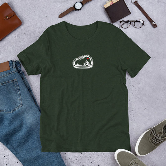 Green t-shirt with a white graphic on a gray surface with jeans, shoes, and accessories.