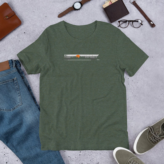 Green t-shirt with explore design on concrete surface with jeans, shoes and accessories.