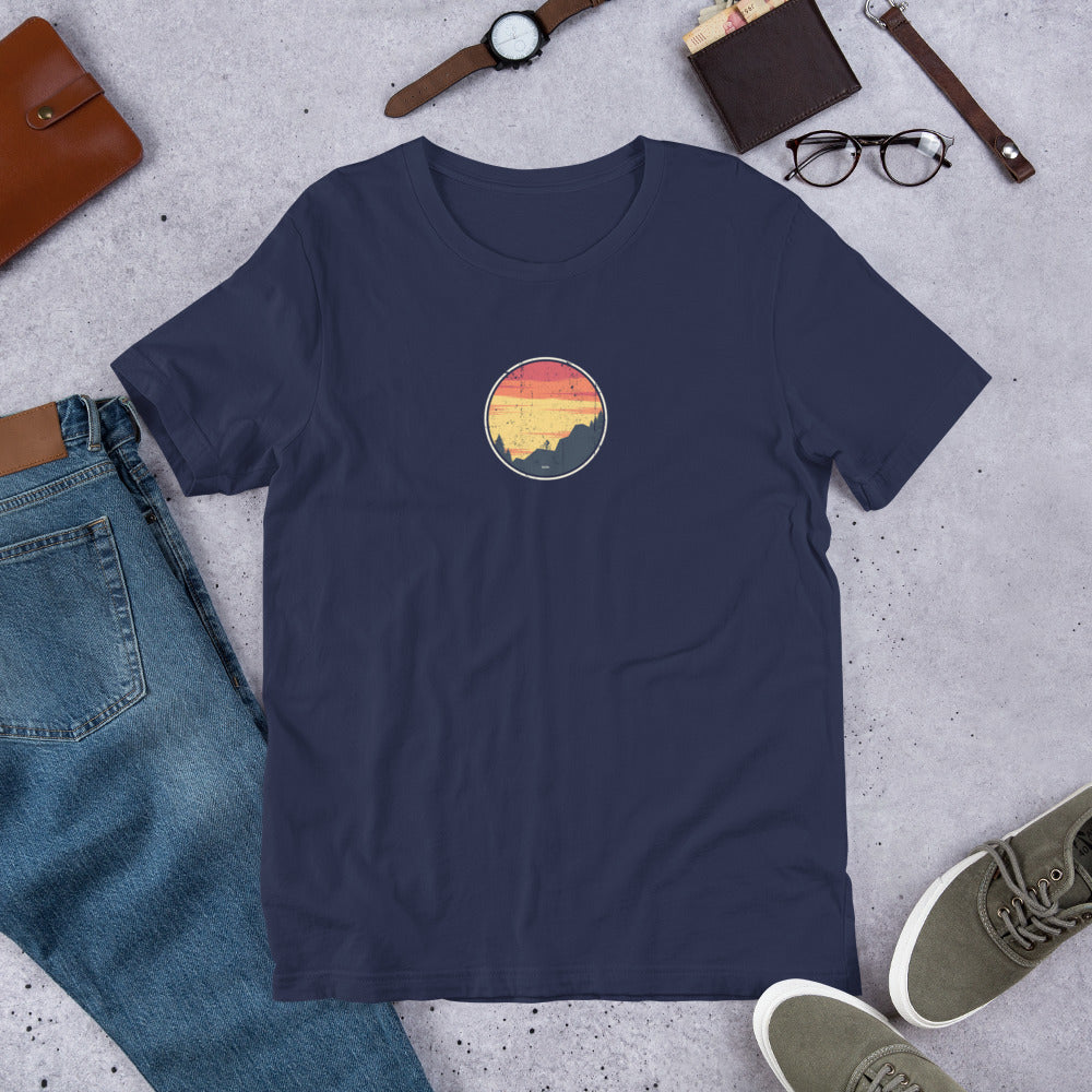 Dark blue t-shirt with vintage mountain bike design on grey surface with jeans, shoes and accessories.